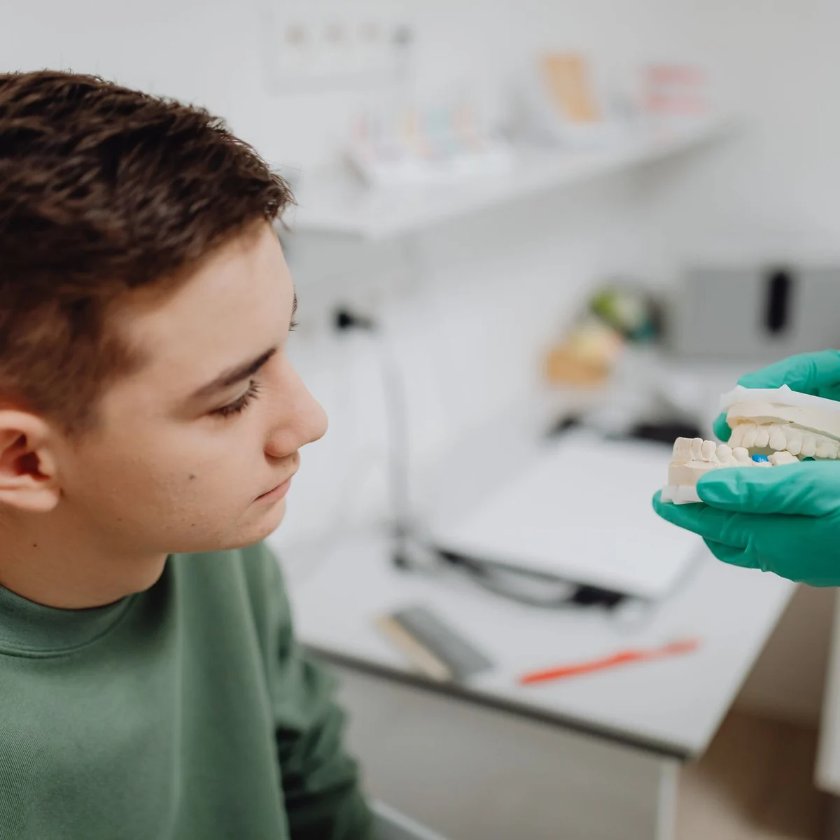 Nastolatek na konsultacji ortodontycznej ogląda model zębów